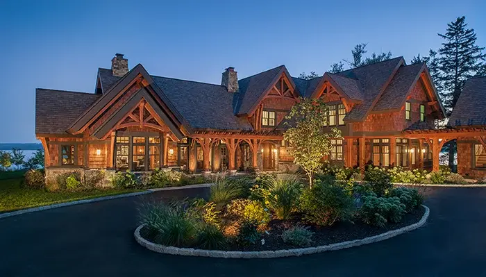 Luxury timber frame home exterior with exposed timber trusses and illuminated evening facade